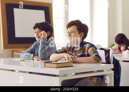 Portrait of two elementary school boys sitting in class and listening to the teacher. Stock Photo