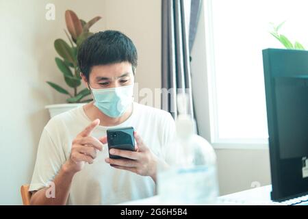 Asian man administrator staff call center in home service office assistance work from home looking data customer from computer communication during co Stock Photo