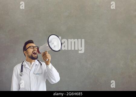 Studio shot of male doctor screaming shouting in megaphone to message heard Stock Photo