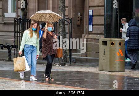 Dundee, Tayside, Scotland, UK. 6th July, 2021. UK Weather: A cloudy and wet day with outbreaks of light rain across North East Scotland with temperatures reaching 17°C. Local residents are still well aware of the social distancing guidelines and the wearing of face masks whilst outside. Shoppers who are caught out in the sudden downpours are sheltering underneath their brollies whilst out shopping in Dundee city centre. Credit: Dundee Photographics/Alamy Live News Stock Photo