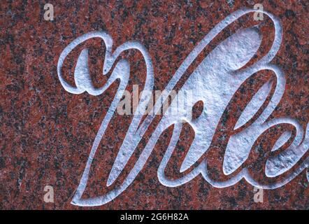 Letters carved in granite marble or some other type of stone. Sandblasted artistic text. Red polished stone Stock Photo