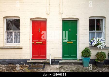 two doors, a red one and a green with windows on a facade of an old house Stock Photo