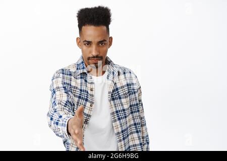 Serious and confident young african american man stretch out hand for handhsake, frowning and looking determined, greeting people, attend business Stock Photo