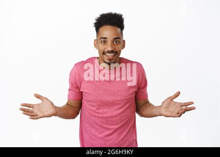 Surprised and happy african american guy spread hands sideways in complete disbelief, did know nothing, looking amazed at camera, white background Stock Photo