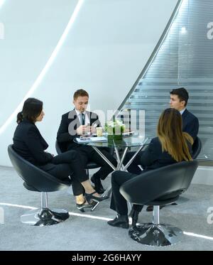 Two men and two women, managers, negotiating in the meeting room sitting at the table. Exhibition Arms and Safety. October 08, 2019. Kiev, Ukraine Stock Photo