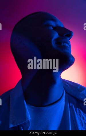 Cinematic portrait of handsome young man in neon blue pink lighted room, stylish male model indoors. Reflection effect Stock Photo