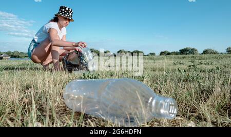 Collecting plastic garbage. The girl collects plastic bottles. Environmental pollution. Stock Photo