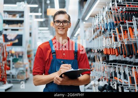 adviser in a hardware store making notes about the availability of goods on the shelves. Stock Photo