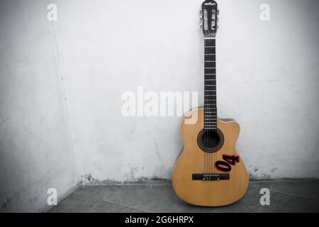 Guitar leaning against a white wall Stock Photo