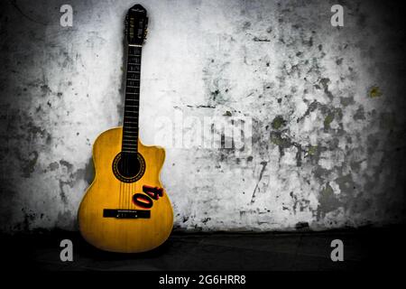 Guitar leaning against a white wall Stock Photo