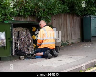 BT Openreach telecoms technician, looking in wiring cabinet on London street,
