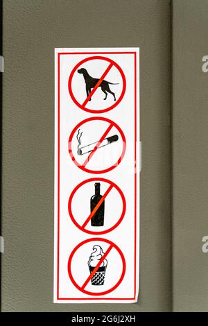 Signs prohibiting dogs, smoking, drinking, ice cream on property, pasted outside near entrance Stock Photo