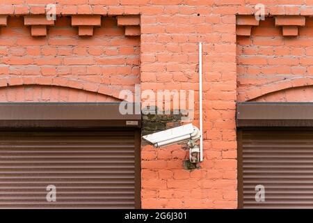 Security camera mounted on brick wall near bordered up windows on building Stock Photo