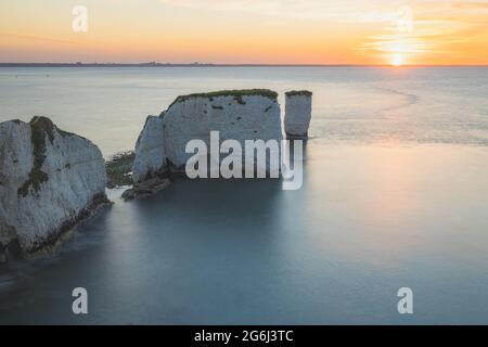Colourful, idyllic sunset or sunrise sky over seascape landscape of the white chalk cliffs and sea stacks of Old Harry Rocks on the Jurassic Coast in