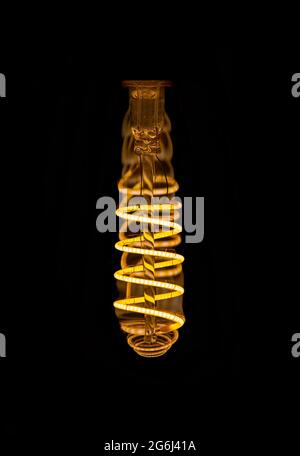 Close up view inside spiral LED decorative light bulb at dark. Copy space. Stock Photo