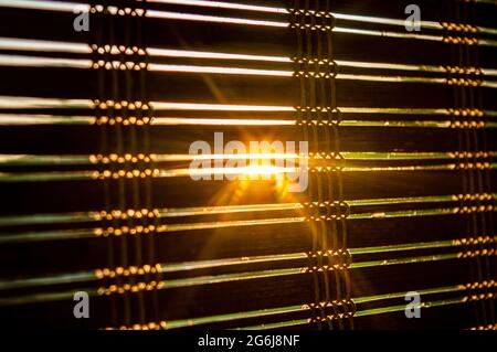the evening sun peeking through the curtain. sunset moment. sunlight filtering through the wooden shutter. that moment. golden hour photo shoot Stock Photo