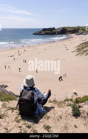 Staycation UK; a woman looking over Broad Haven beach in summer sunshine, Stackpole Estate, Pembrokeshire Coast, Pembrokeshire Wales UK Stock Photo