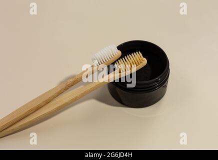 A set of eco-friendly bamboo toothbrushes and black tooth powder on a beige pastel background. Zero-waste, sustainable lifestyle. Plastic-free concept Stock Photo