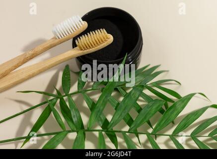A set of eco-friendly bamboo toothbrushes and black tooth powder on a beige pastel background. Zero-waste, sustainable lifestyle. Plastic-free concept Stock Photo