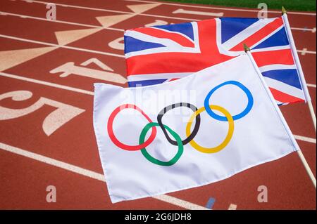 MIAMI, USA - AUGUST, 2019: An Olympic and British union jack flag flutter together above the starting line of a red athletics track. Stock Photo