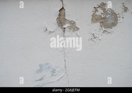 cracked house wall affected by rains and earthquakes. former crack white house wall. Old wall of a building or house with cracks. cement floor Stock Photo