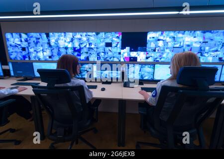 Team working on the System Control Room, Technical Operator Works at His Workstation with Multiple Displays, Security guards working on multiple monit Stock Photo