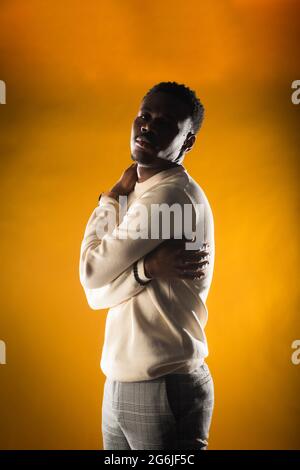 Young black male is touching himself while posing on yellow background Stock Photo