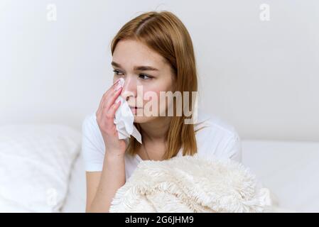 Woman suffering from depression and crying. Young beautiful girl sitting at home and cry wiping away tears with a tissue. Stock Photo