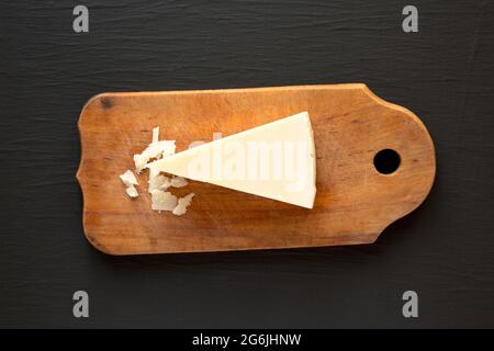 Pecorino Romano Cheese on a rustic wooden board on a black background, top view. Flat lay, overhead, from above. Stock Photo