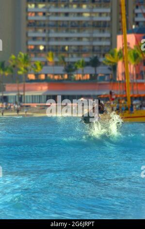 Boogie Boarder goes airborne on the beach of Waikiki in Honolulu, Hawaii.  Evening light is caught in the splash and wake of his wave. Stock Photo