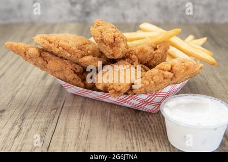 Deep fried meal of strips of breaded chicken and a side order of french fries. Stock Photo