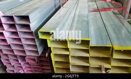 square metal pipe Carbon Steel Pipe Section Stainless steel bars are stacked on top of each other in a metal product warehouse. Stock Photo