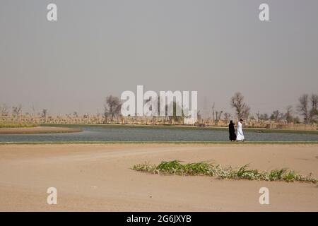 A couple walks along the Love Lakes in Al Qudra, Dubai, UAE. --- The Love Lakes Dubai are made up of two artificial heart shaped lakes. The lake is so
