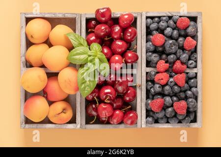blueberries, cherries and peaches in a wooden box Stock Photo