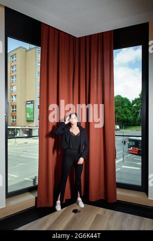 Hamburg, Germany. 12th June, 2021. Yusra Mardini, a swimmer, stands in front of a red curtain in the lounge of a Hamburg hotel. An intersection in Hamburg can be seen in the background. Credit: Gregor Fischer/dpa/Alamy Live News Stock Photo