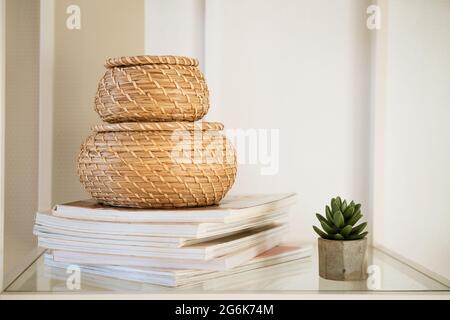 Close-up of a round straw box with a lid on a white shelf. Eco-friendly items for storing small items, organizing space. Home decor decorative items. Stand on a shelf in the room Stock Photo