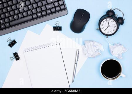 Urgent work, deadline, overwork concept. Keyboard with computer mouse, alarm clock, blank notebook, pen, cup of coffee, crumpled paper on office desk Stock Photo