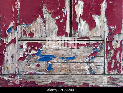 Old red paint cracks and peels away from old grey wood Stock Photo