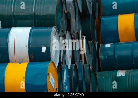 Old chemical barrels stack. Blue, green, and yellow chemical drum. Steel tank of flammable liquid. Hazard chemical barrel. Industrial waste. Empty Stock Photo