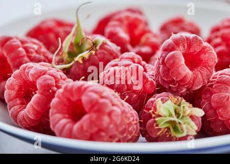 Fresh raspberries lying on white plate close-up shooting selective focus Stock Photo