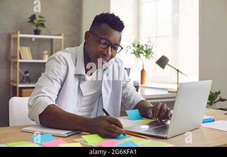 African American man writes notes on stickers while developing a business project in the office. Stock Photo