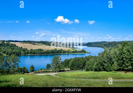Beautifil view on Kaszuby lake district. Lake surrounded by trees and fields on a sunny, summer day.