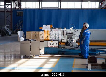 Atyrau,Kazakhstan-May 21,2012: Kazturboremont (KTR) plant interior. Modern turning lathe ZMM Sliven. Workers operator in white hardhat,blue work wear. Stock Photo