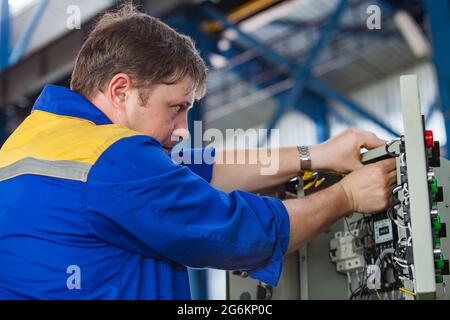 Almaty region,Kazakhstan-June 06,2012: DAMU industrial zone. SONiK factory workshop. Electrician engineer assembling control panel. Switchers, wires a Stock Photo