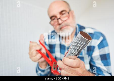 A plumber as a craftsman or do-it-yourselfer repairs shower head with a pipe wrench Stock Photo