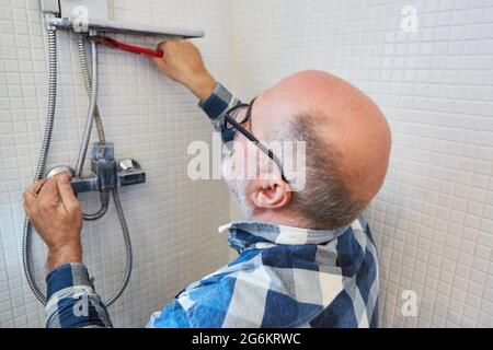 Plumber craftsman assembles new hose on a shower in the bathroom Stock Photo