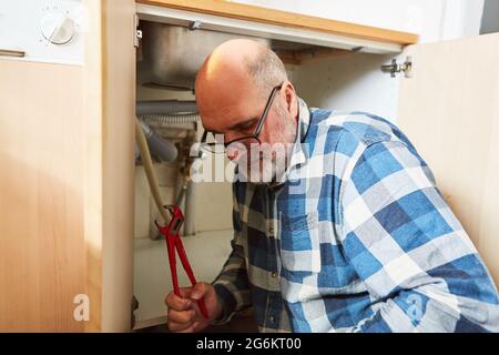 Plumber handyman assembling or repairing the kitchen sink drain Stock Photo