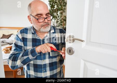 Man as handyman tradesman when changing door lock or repairing it at home Stock Photo