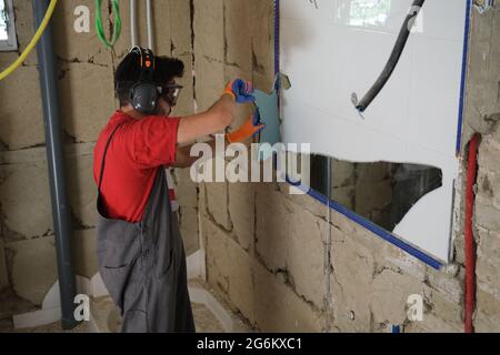 Builder removing a mirror from a wall. House renovation. Stock Photo