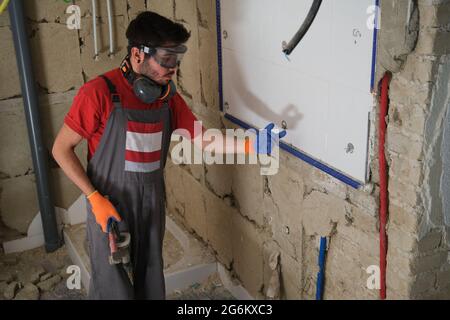 Builder wearing protective gloves and glasses, holding a hammer. House renovation. Stock Photo